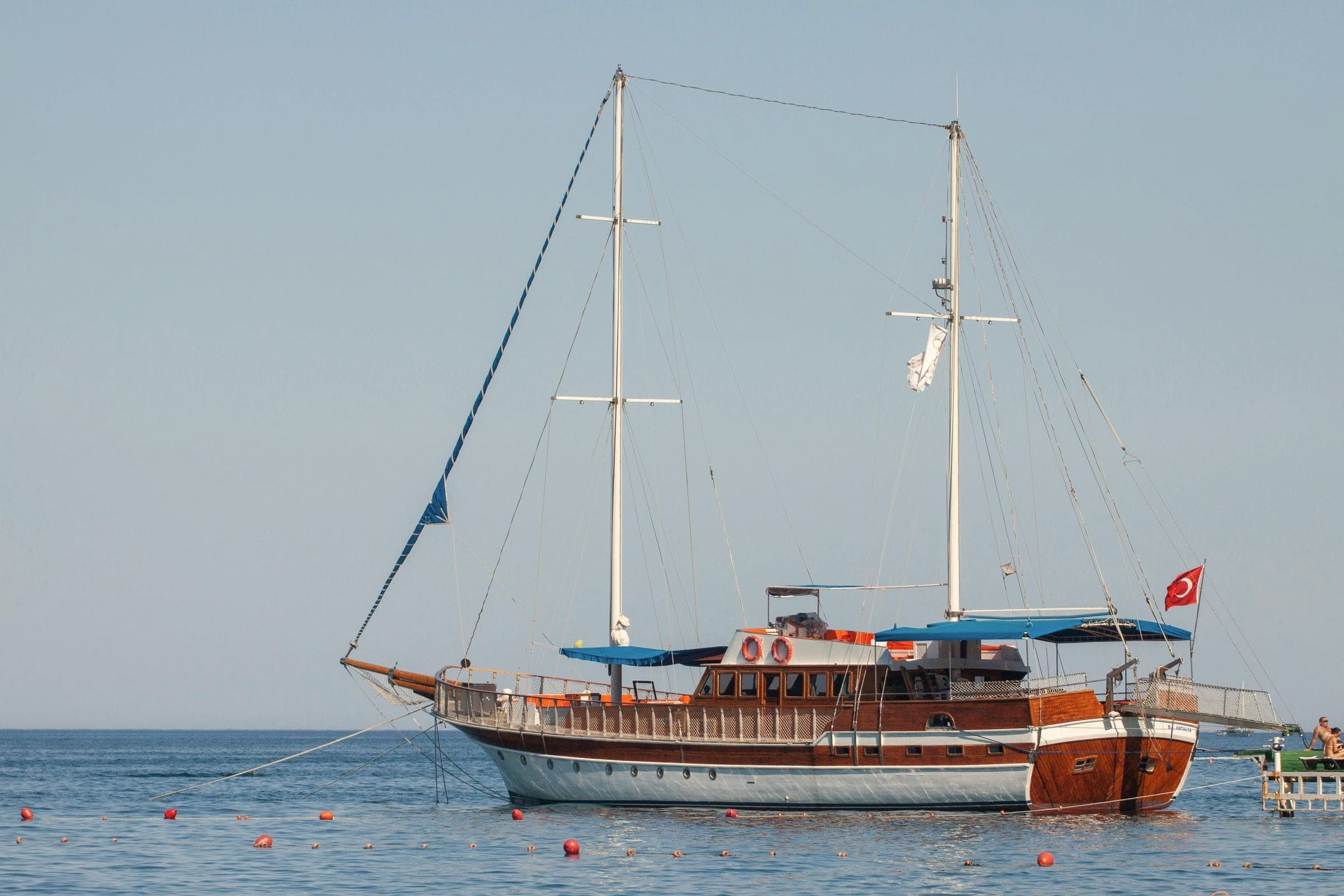 A wooden gulet flying a Turkish flag, anchored in calm sea